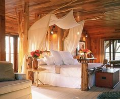 an old photo of a bed in a room with wood walls and ceiling, covered by white drapes