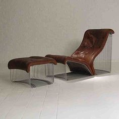 a brown leather chair and ottoman sitting on top of a white tile floor next to a wall