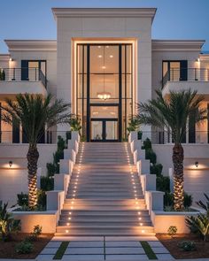 a large white building with steps leading up to the front door and palm trees on either side