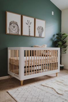 a baby's room with green walls and white crib in the corner, two framed pictures on the wall