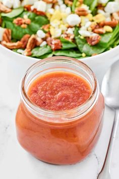 a close up of a bowl of salad and a jar of dressing on a table