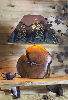 a wooden table with a lamp on top of it next to a teapot and tree stump