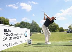 a man in black shirt and white pants swinging a golf club at the bmw championship