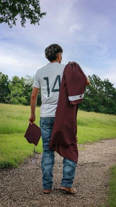 a man walking down a dirt road carrying a bag