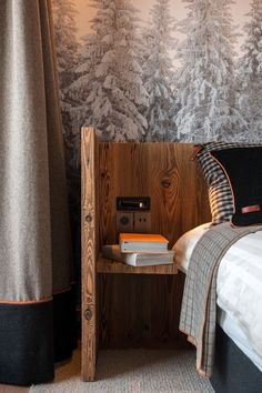 a bed room with a neatly made bed next to a wall papered forest scene