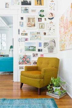 a yellow chair sitting in front of a wall full of pictures