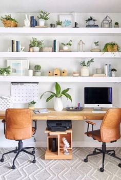 a desk with two chairs and a computer monitor on it in front of some shelves