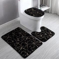 two black and white bathroom rugs next to a toilet with the lid up on it