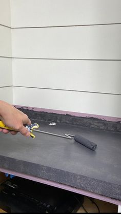 a person using a pair of scissors to cut the edge of a piece of concrete