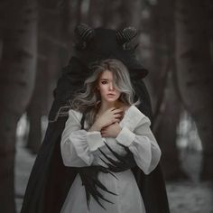 a woman dressed as a demon standing in the woods with her hands on her chest