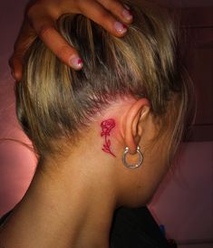 a woman with a small tattoo on her left side behind the ear is looking down