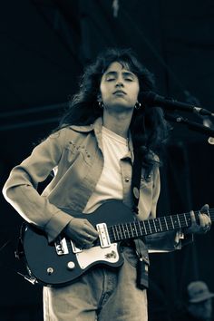 a woman with long hair playing an electric guitar at a music festival in black and white