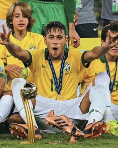 two soccer players sitting on the ground with their hands in the air while holding trophies