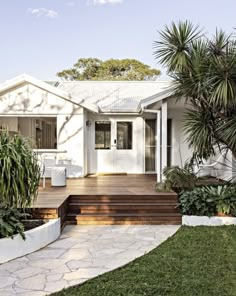 a white house with wooden steps leading up to the front door and covered patio area