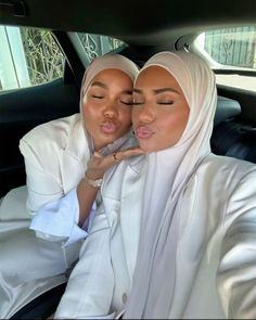 two women sitting in the back seat of a car with their faces close to each other