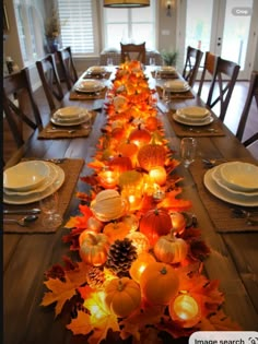 a long table is decorated with candles and pumpkins