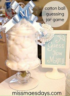 a glass jar filled with cotton balls on top of a table next to a sign