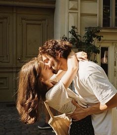 a man and woman kissing in front of a building