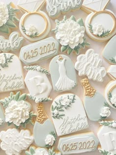 wedding cookies decorated with white flowers and gold trimmings are displayed on a table