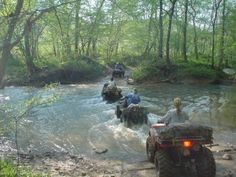 four people are riding atvs through the water