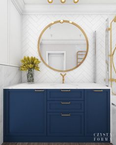 a bathroom with blue cabinets and a round mirror on the wall above it, along with gold accents