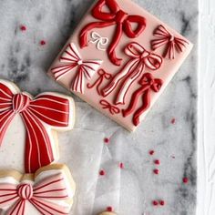 two decorated cookies sitting next to each other on top of a marble counter with red and white icing