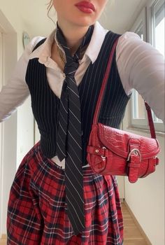 a woman wearing a skirt and tie holding a red purse