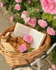 a basket full of croissants sitting on top of a bike next to pink flowers