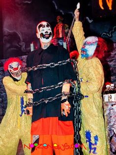 two clowns with painted faces and chains on their face are standing in front of a stage