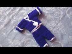 a crocheted baby's outfit laying on a bed with blue and white fabric