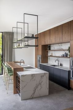 an open kitchen with marble counter tops and wooden cabinets, along with green bar stools