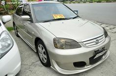 a silver car with a for sale sign on it's windshield is parked next to another white car