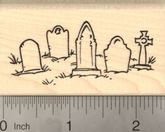 a wooden rubber stamp with a drawing of graves and crosses on the ground next to a ruler