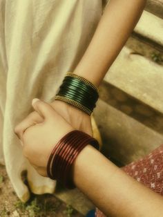 two people are holding hands with bracelets on their wrists and one is wearing a white shirt