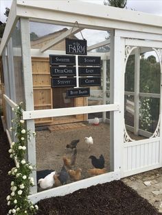 several chickens in a small white coop with a sign on the door that says farm