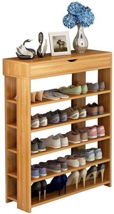 a wooden shoe rack with several pairs of shoes on it and a vase filled with blue flowers