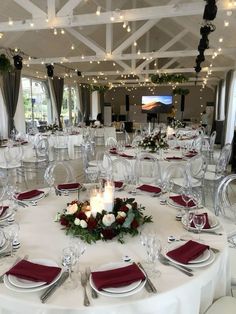 a banquet room set up with white table cloths, red napkins and silverware