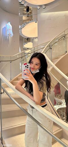 a woman taking a selfie while standing on the stairs in front of an escalator