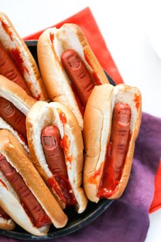 hotdogs with ketchup and mustard in a black bowl on a purple napkin