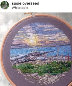 an embroidery project with the sun setting over water and grass on it's side