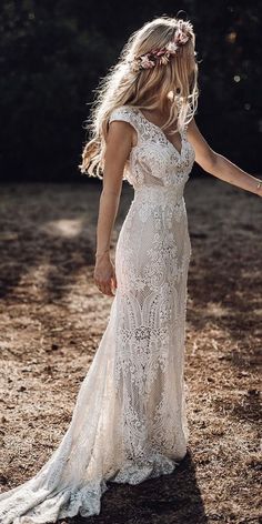 a woman in a white dress is walking through the dirt