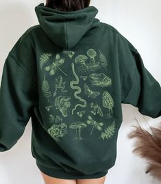 Everyone needs a cozy go-to hoodie to curl up in, so go for one that's soft, smooth, and stylish. It's the perfect choice for cooler evenings and sitting around the campfire! With vintage illustrations of frogs, mushrooms and insects for a goblincore, forestcore or cottagecore aesthetic, featuring a bunch of little forest critters! This unisex heavy blend hooded sweatshirt is relaxation itself, the material is a thick blend of cotton and polyester, this makes for a plush, soft feel alongside war Dark Academia Hoodie, Insects Illustration, Mushroom Frog, Hoodies Aesthetic, Goblin Core, Earthy Outfits, Vintage Mushroom, Dark Academia Aesthetic, Green Hoodie