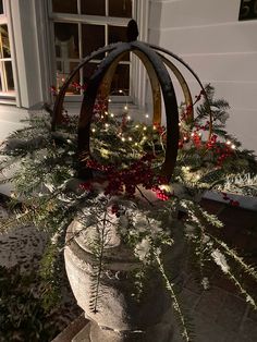 a planter filled with christmas greenery and lights on the side of a house