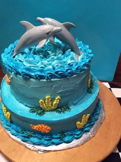 there is a cake with blue frosting and a dolphin on top