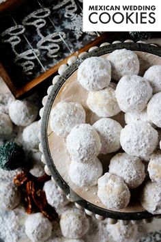 a bowl filled with snowball cookies on top of a table next to other decorations