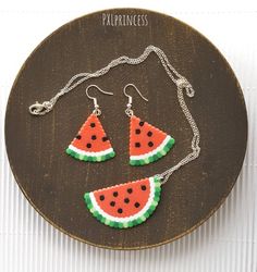 a pair of watermelon slices are hanging from a necklace and earring set