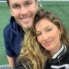 a man and woman posing for a photo on a soccer field with grass in the background