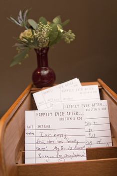 there is a vase with flowers in it and some paper on the table next to it