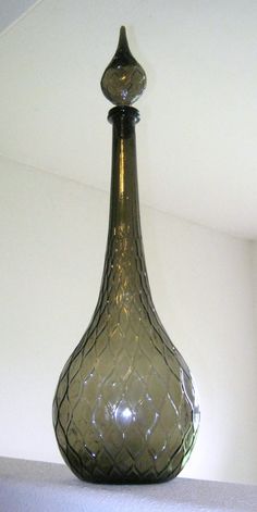 a glass vase sitting on top of a white shelf in front of a light fixture