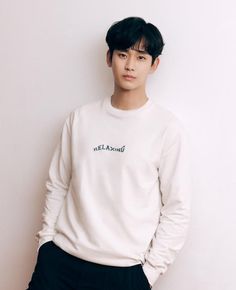 a young man standing in front of a white wall with his hands on his hips